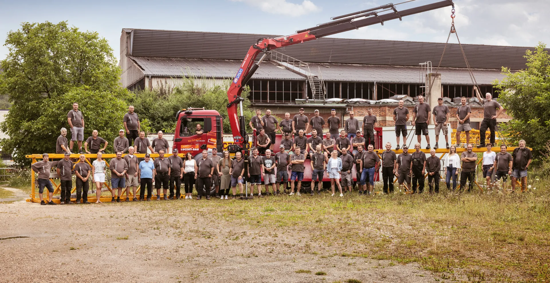 Gruppenbild der Belegschaft von Luczky-Bau vor einem Lkw mit Ladekran