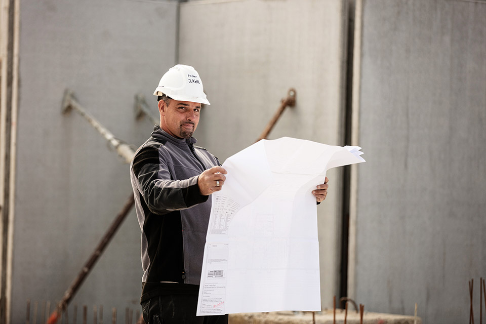 Bauleiter mit Helm studiert einen Bauplan